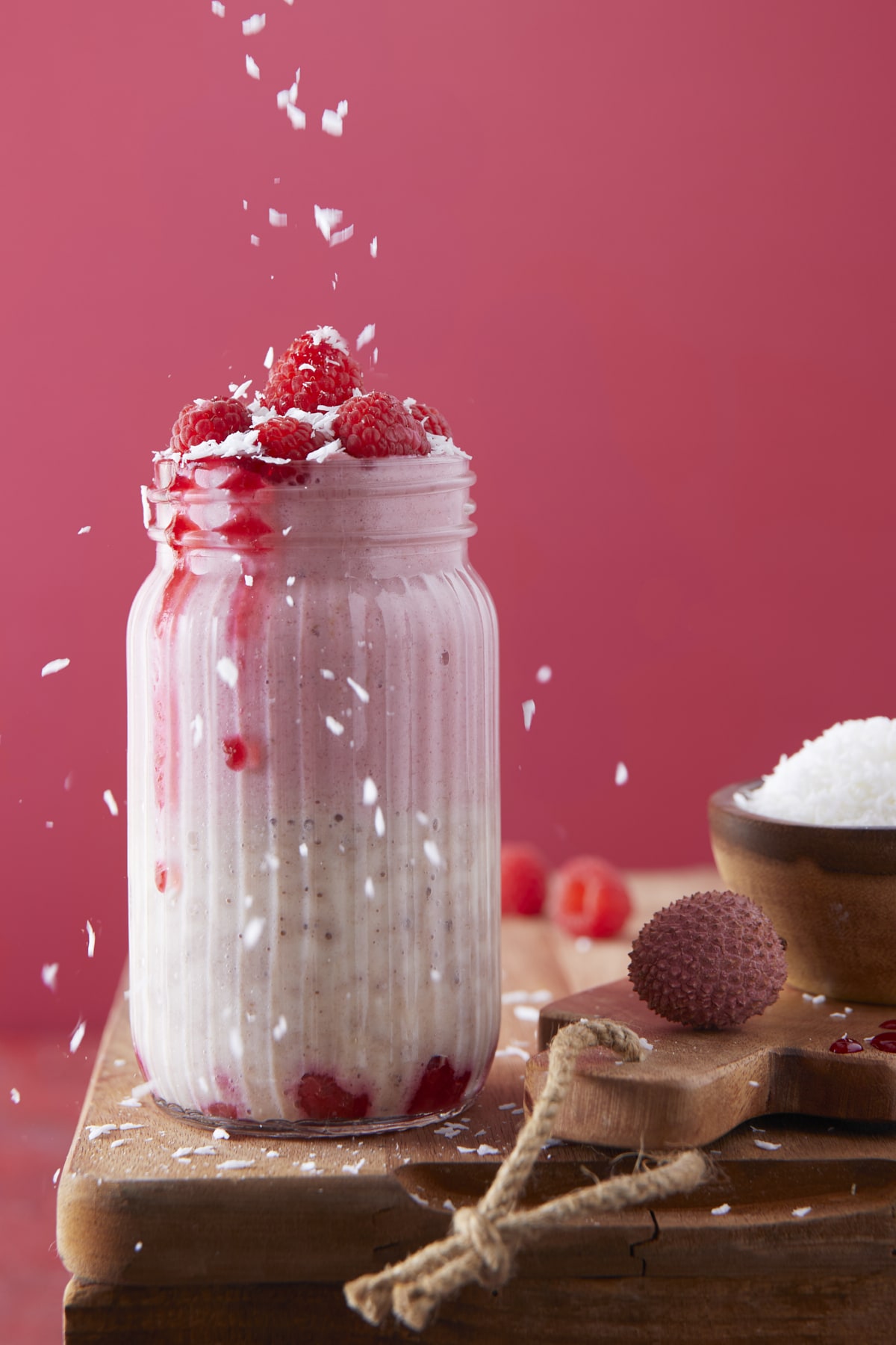 Noix de coco saupoudrée au-dessus d’un smoothie framboises-litchis