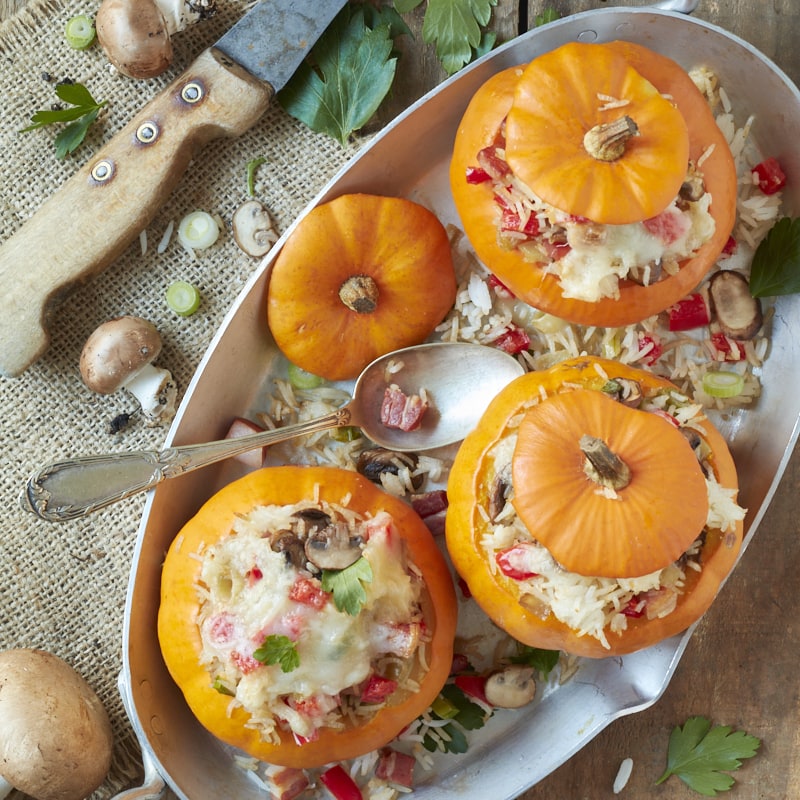 Flatlay sur un plat de courges farcies de riz aux légumes et aux lardons.