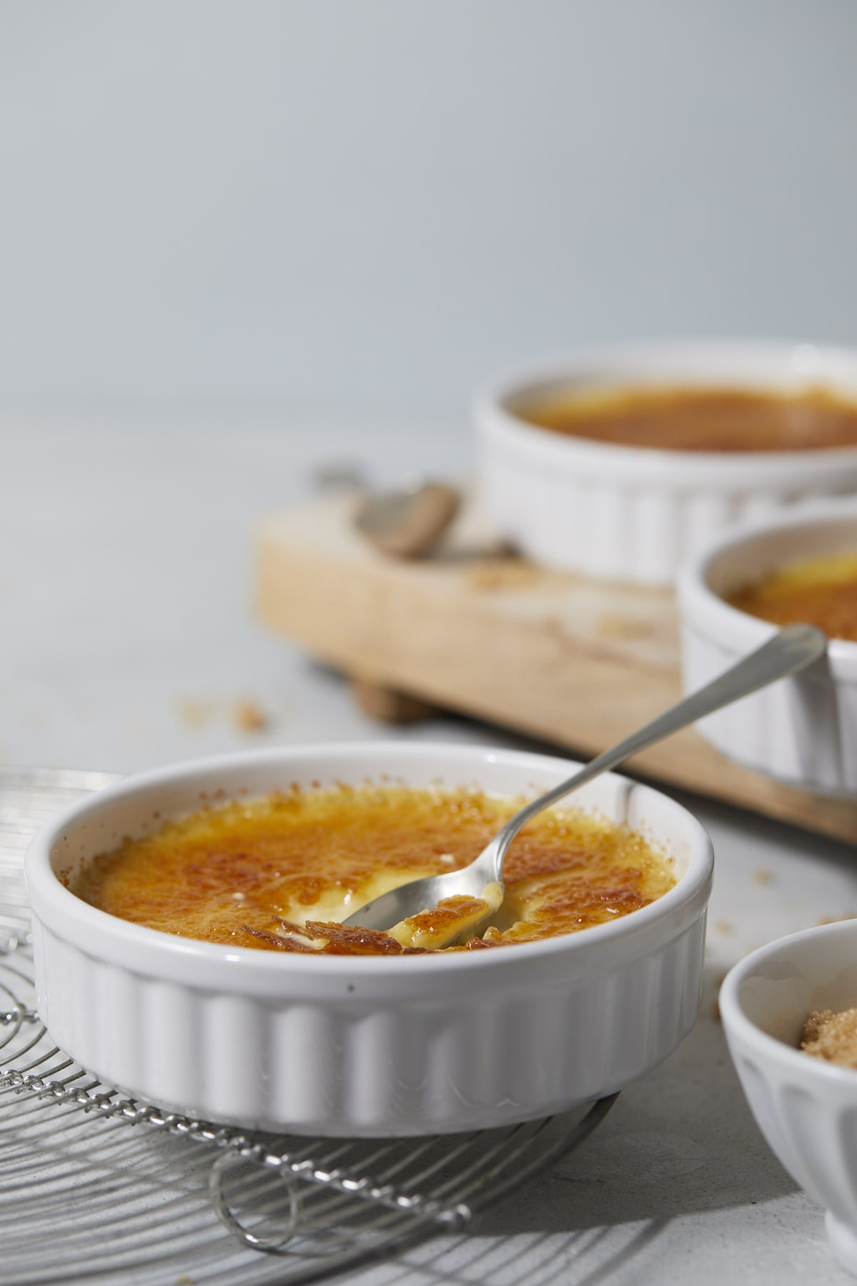 Cuillère cassant la croûte d'une crème brûlée à la vanille.