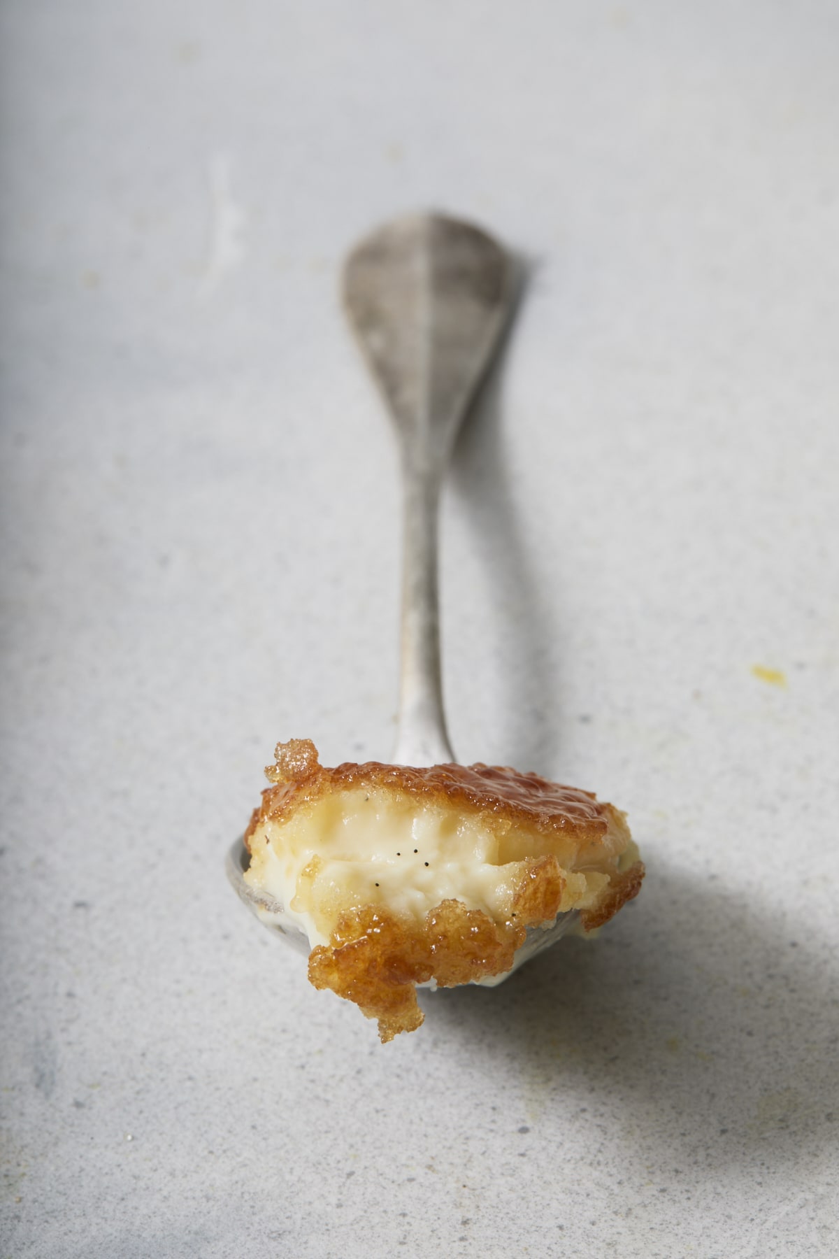 Cuillère de crème brûlée à la vanille avec une croûte de sucre caramélisé.