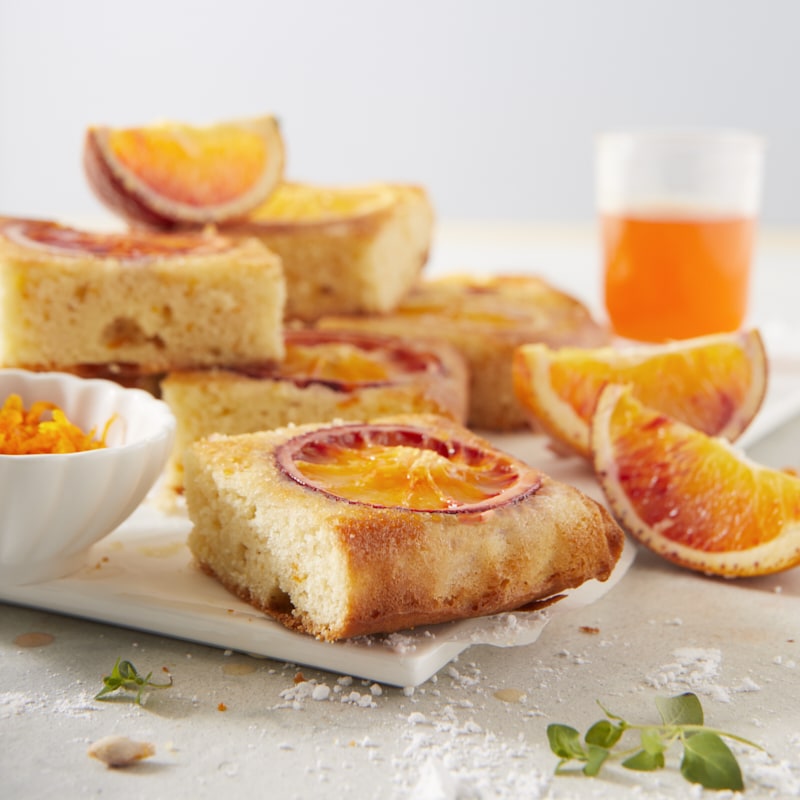 Parts de gâteau renversé aux oranges sanguines empilées, photographiées de face.
