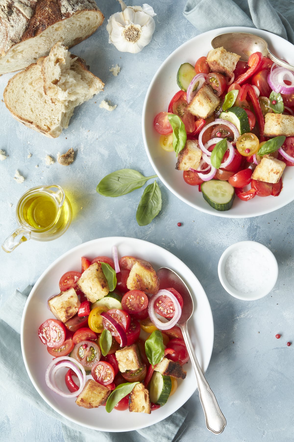 Deux assiettes de panzanella, accompagnées d'huile d'olive et de pain.