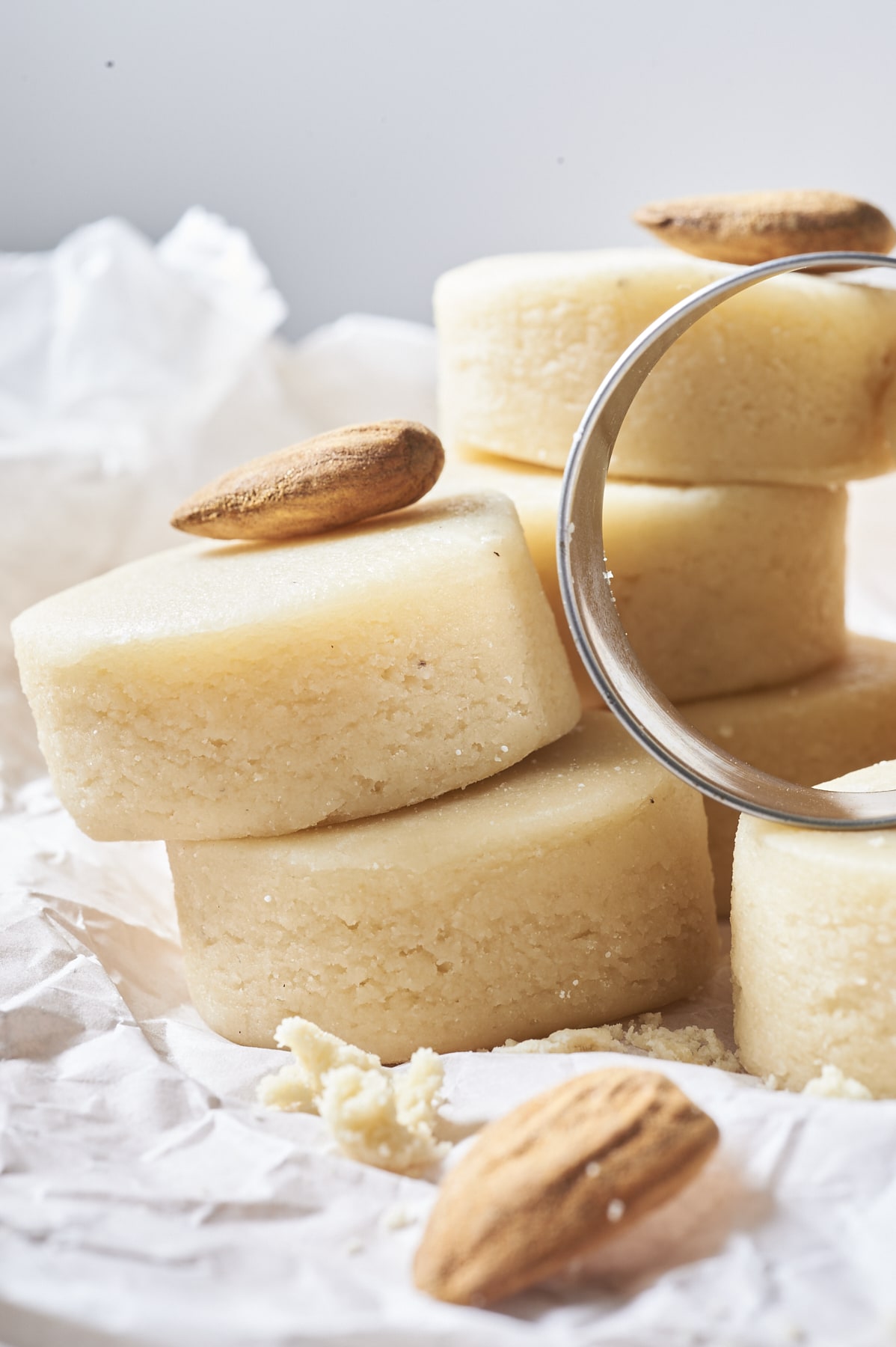 Des pâtes d'amandes empilées ainsi que quelques amandes et un emporte-pièce.