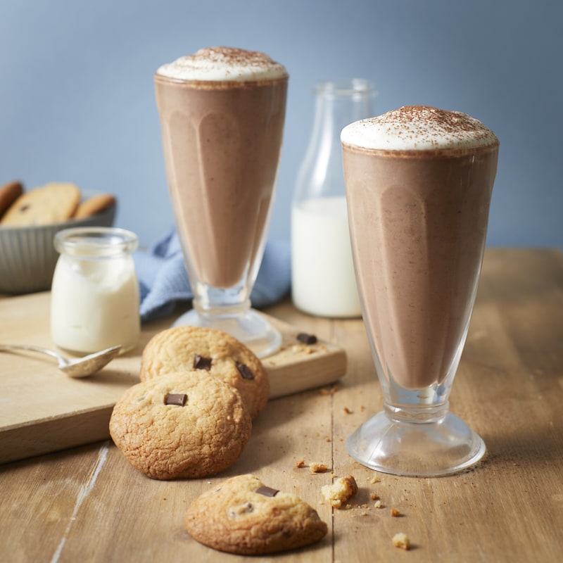 Smoothie avocat cacao servi avec de la crème fouettée à la vanille et des cookies au chocolat