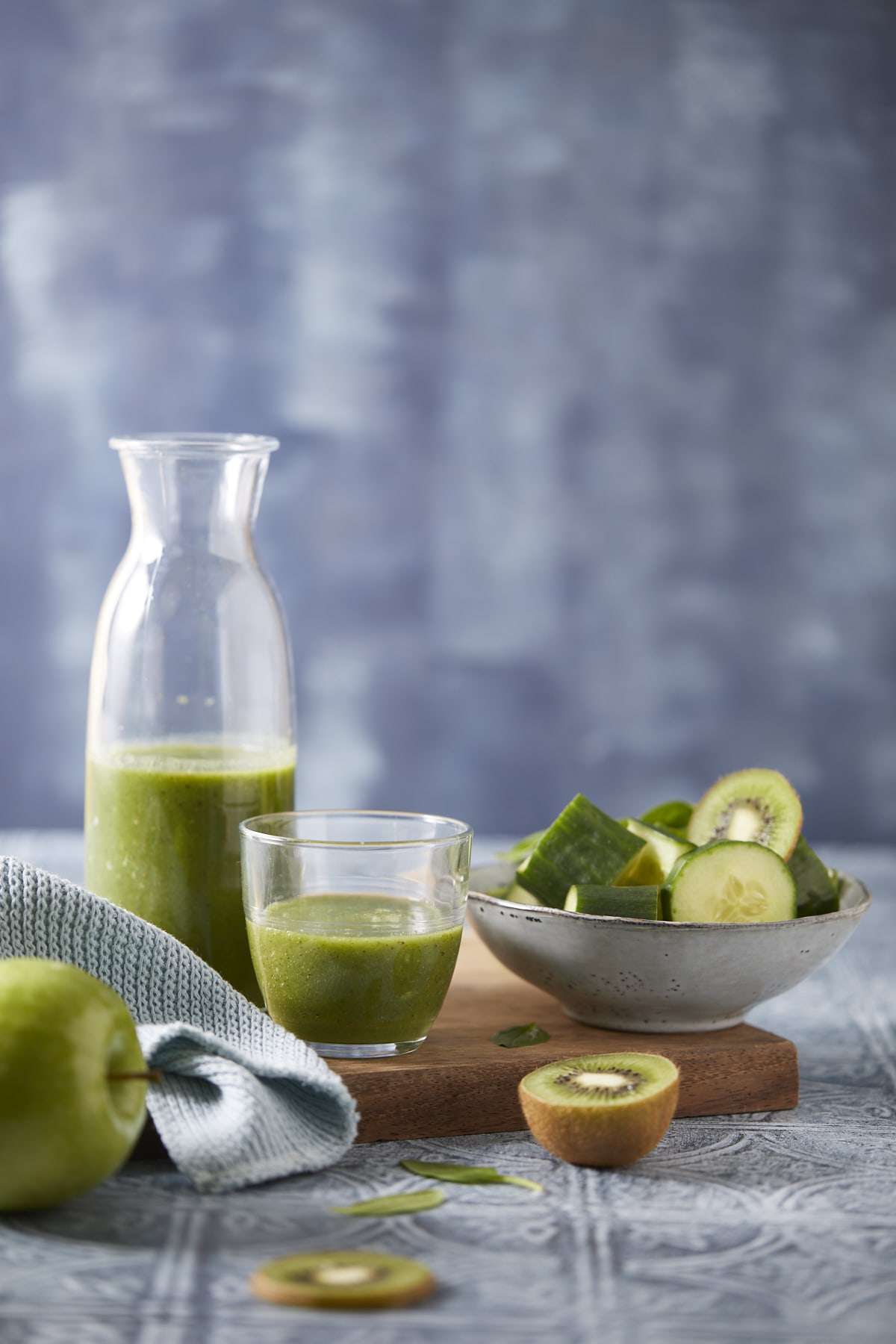 Smoothie vert pomme concombre kiwi dans une bouteille et un verre avec concombre, kiwi et épinards