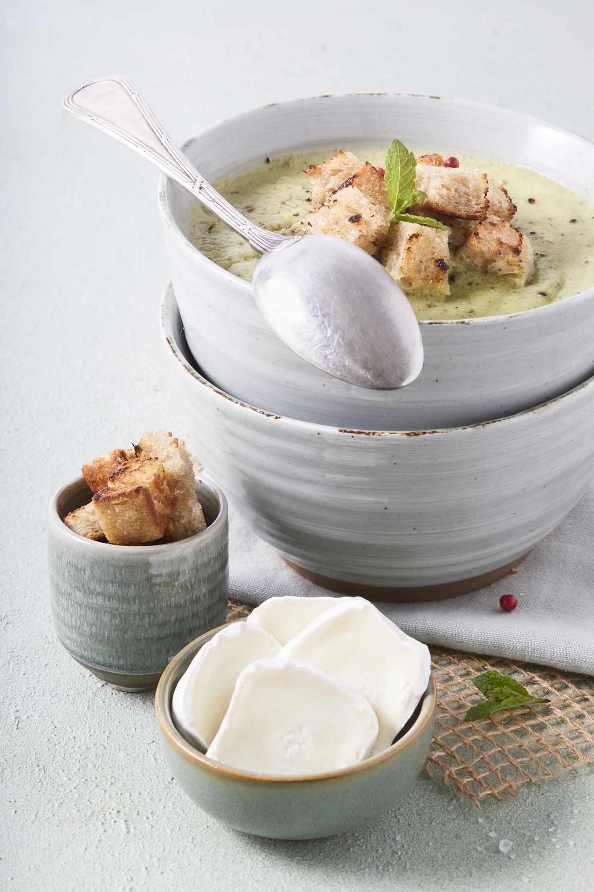 Un bol de soupe froide de courgettes à la menthe avec en accompagnement des croûtons.