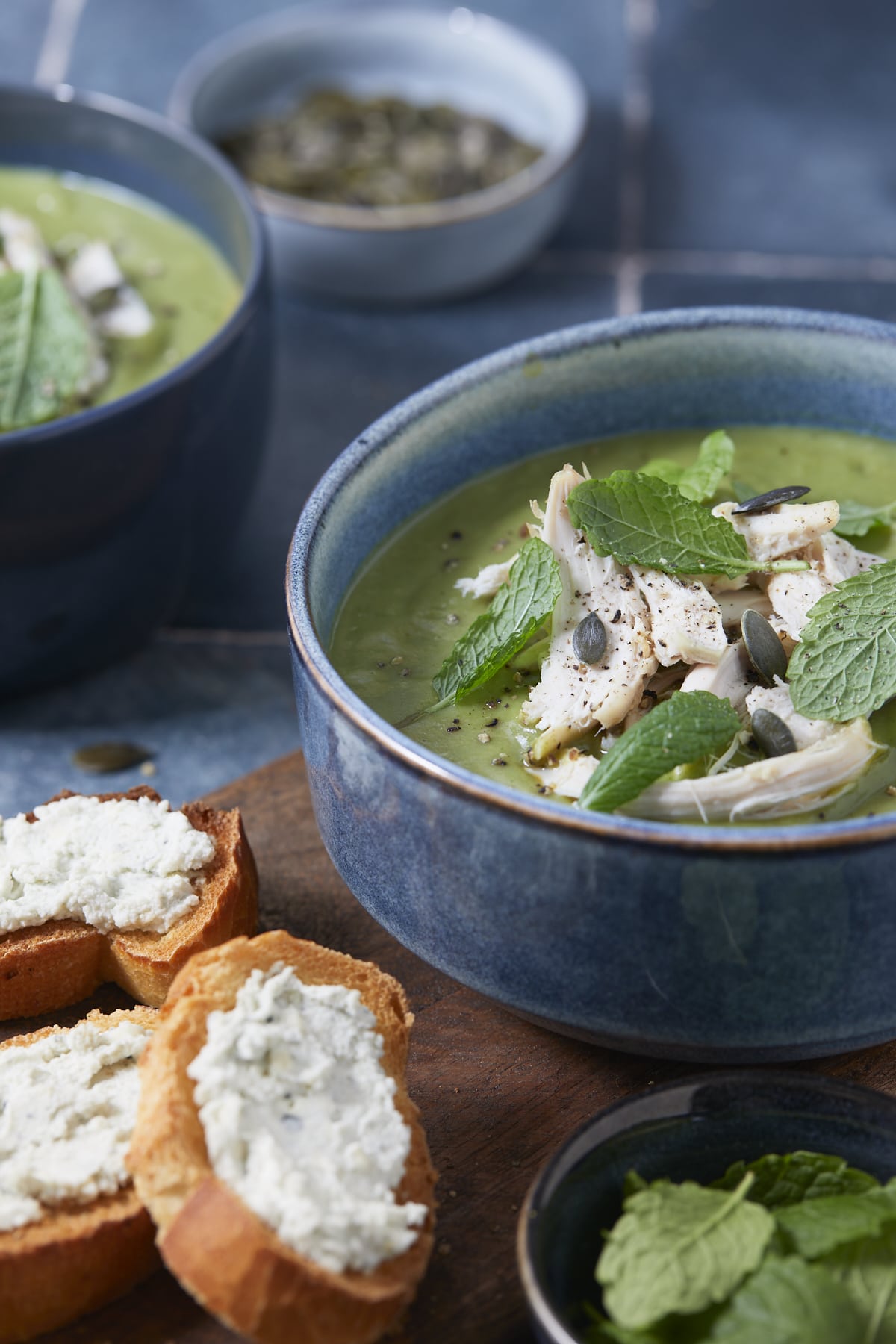 Soupe repas de brocolis poulet menthe servie dans des bols, garnie de pépins de courges et accompagnée de toasts au fromage.