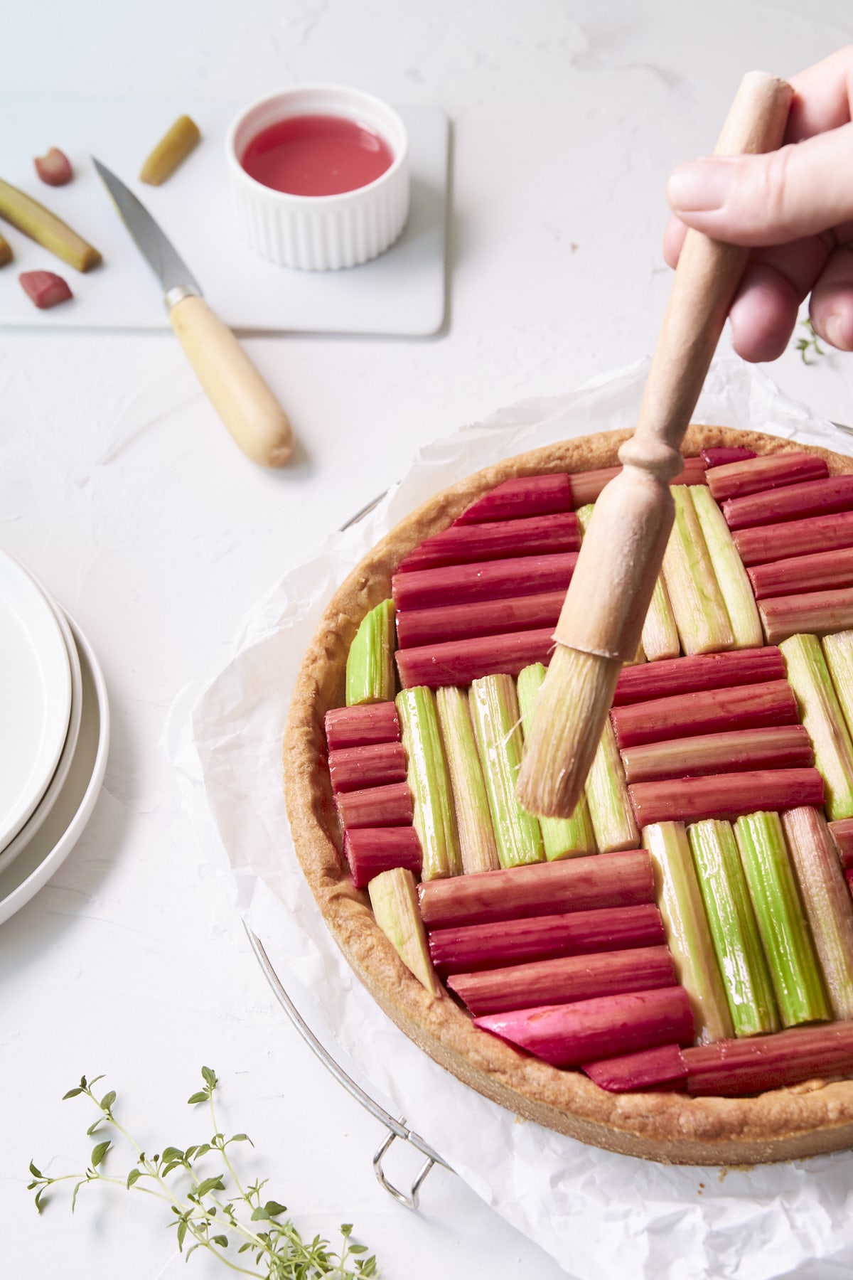 Une tarte géométrique à la rhubarbe est en train d'être badigeonnée de sirop.