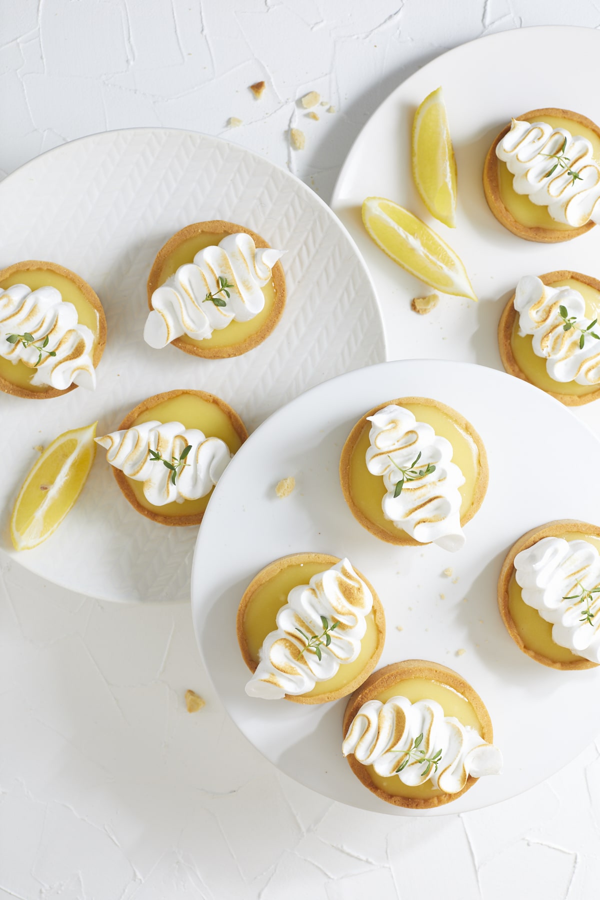 Tartelettes citron meringuées servies sur des assiettes blanches