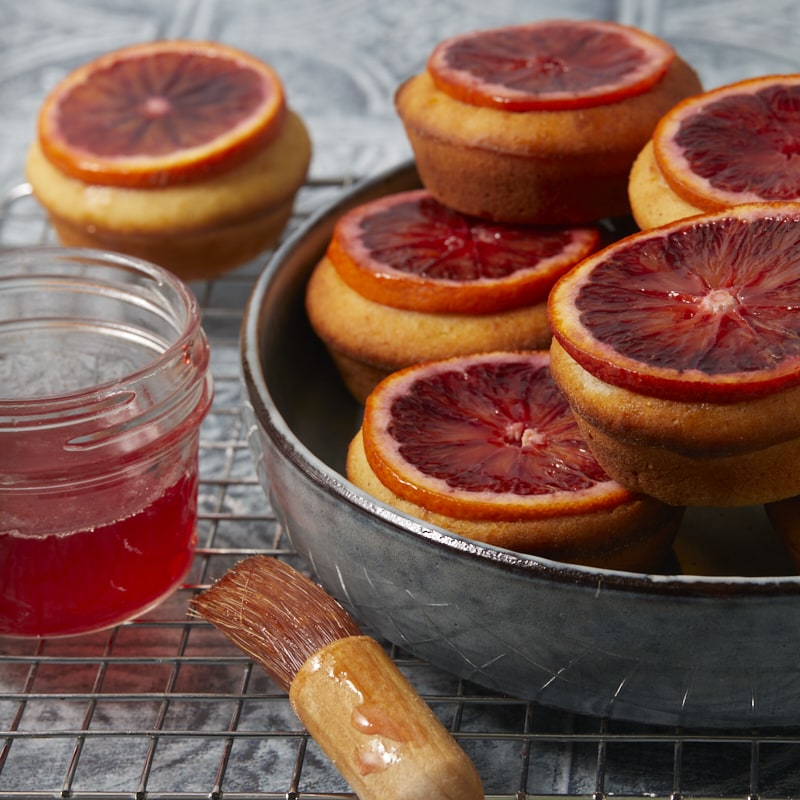 Mini-cakes dorés recouverts de tranches d'oranges sanguines et de sirop.