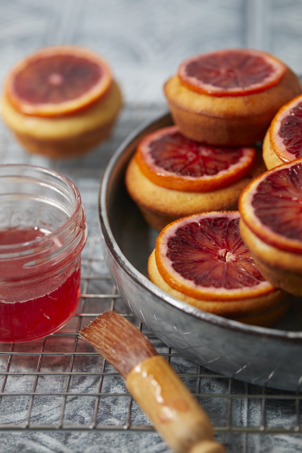 Gros plan sur des mini-cakes aux oranges sanguines imbibés de sirop présentés dans un plat.