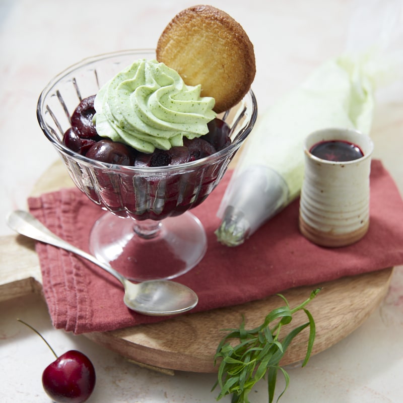 Une coupe de compote de cerises garnie de chantilly à l'estragon et accompagnée d'un sirop de cerises