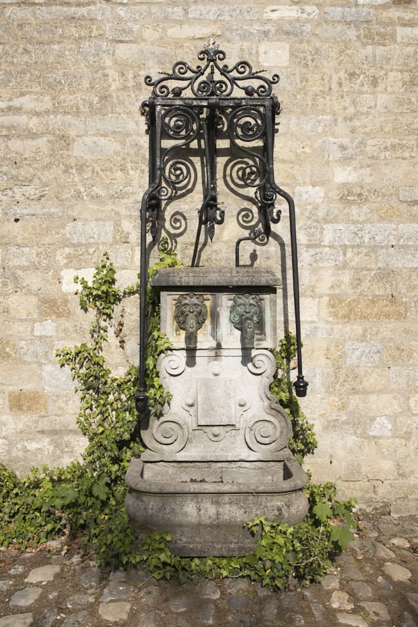 Une fontaine ancienne cerclée de ferronnerie.
