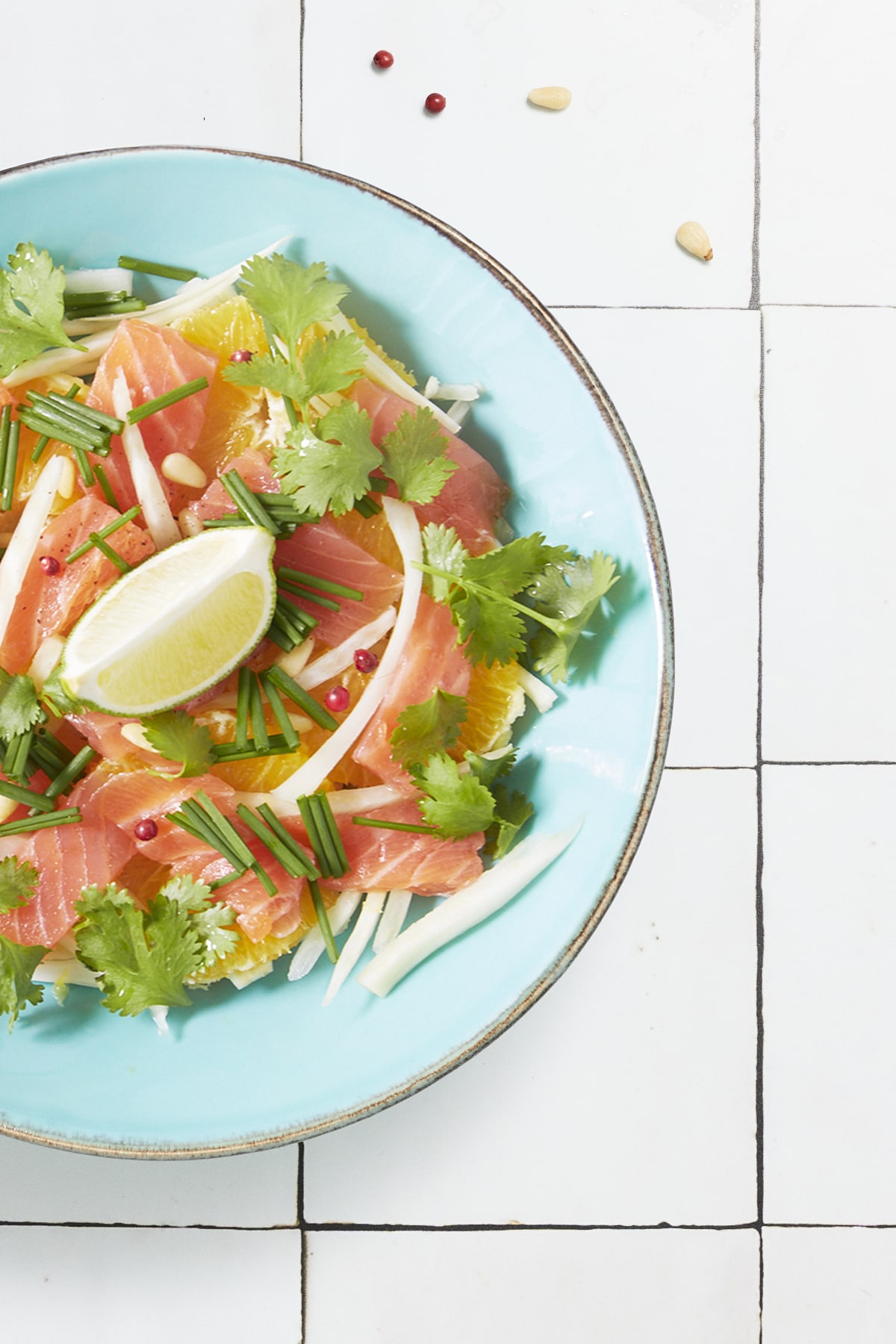 Gros plan en flatlay sur une salade composée de fenouil, de tranches d'oranges, de lamelles de saumon fumé et de feuilles de coriandre.