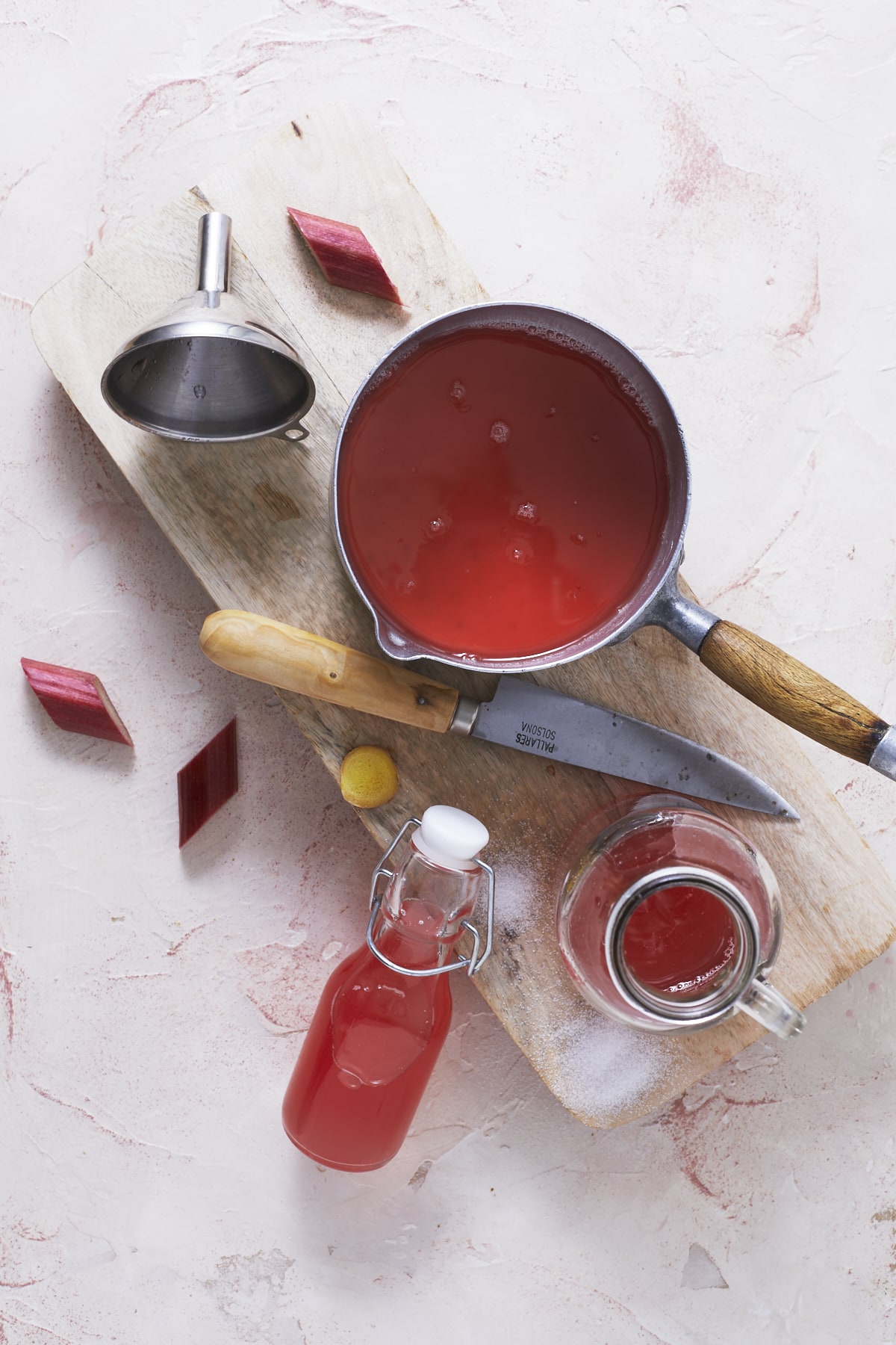 Une casserole de sirop de rhubarbe au gingembre et deux bouteilles.