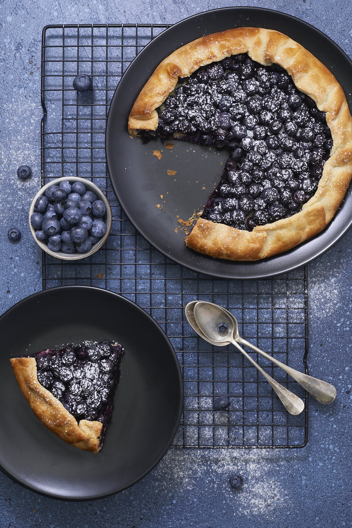 Tarte rustique aux myrtilles coupée et une assiette à dessert avec une part de tarte.