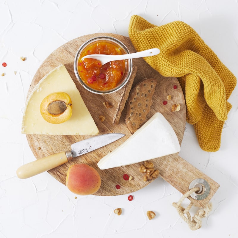 Un plateau de fromage accompagné d'un pot de chutney aux abricots