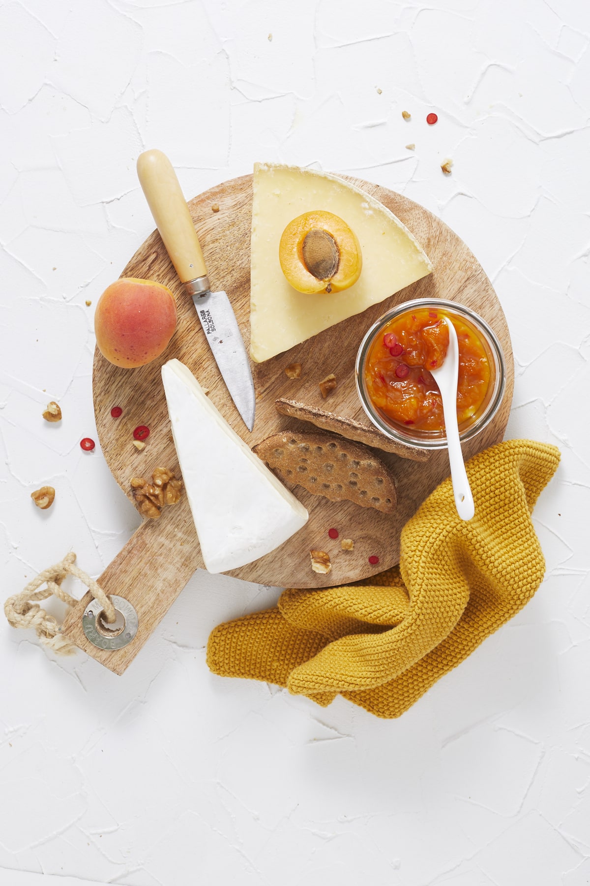 Un plateau de fromage en flatlay avec des abricots, des crackers, du chutney aux abricots et des noix.