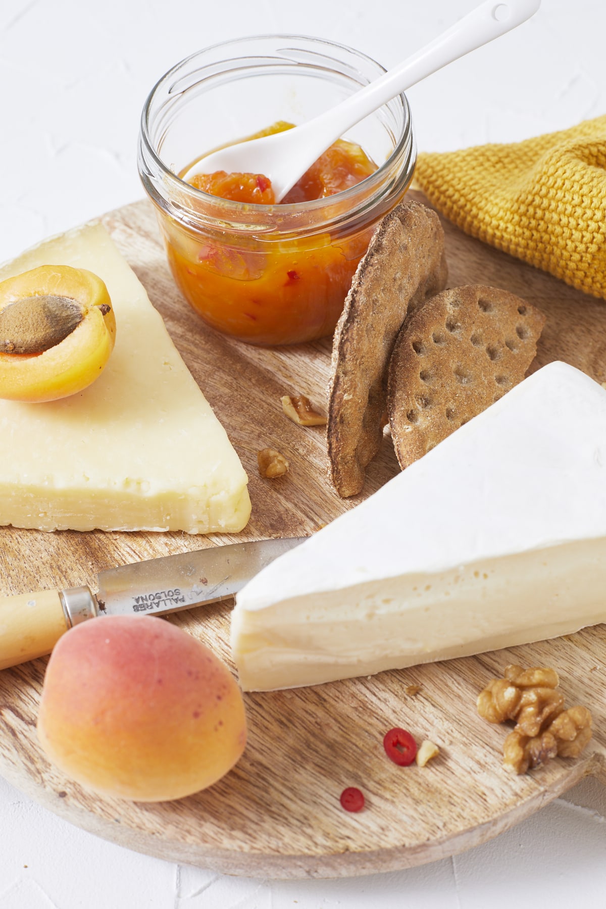Gros plan sur un plateau de fromage accompagné de crackers, de chutney aux abricots et de noix
