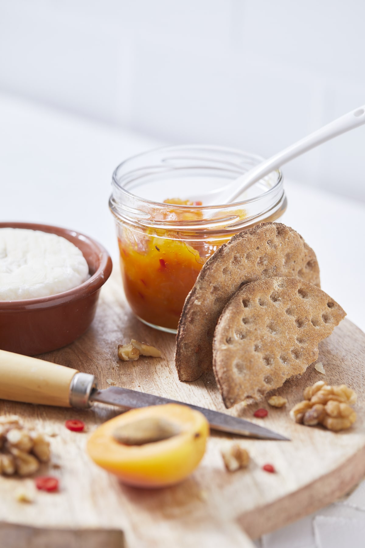 Un pot de chutney aux abricots avec du Saint-Marcelin, des crackers et des noix.