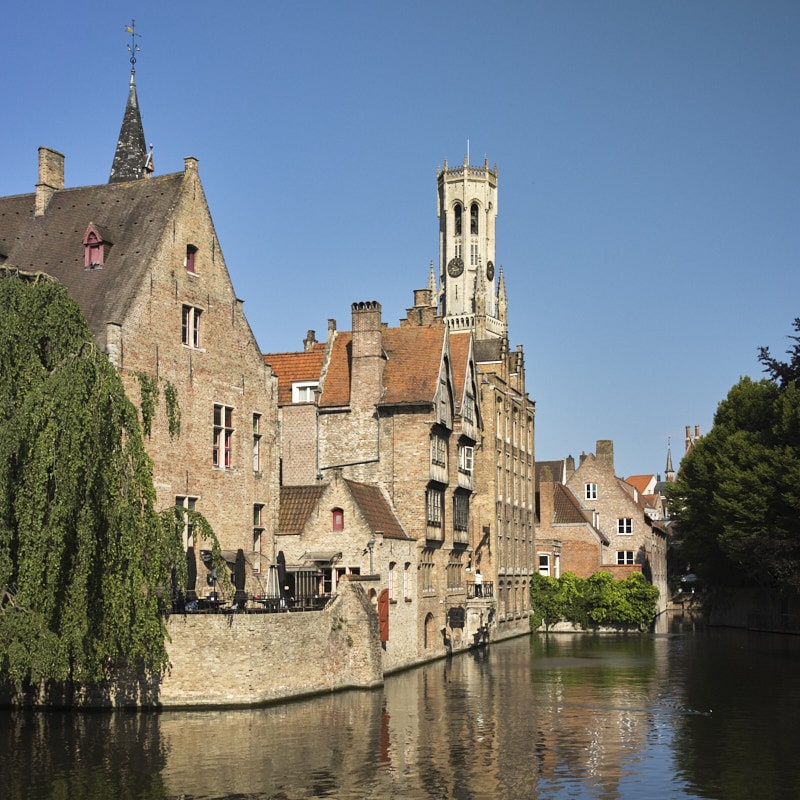 Maisons historiques et beffroi de Bruges se reflétant dans un canal