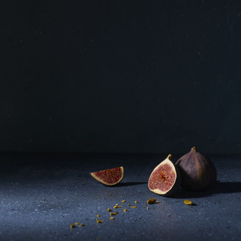 Figues sur fond bleu sombre avec grand espace négatif en photographie culinaire moody
