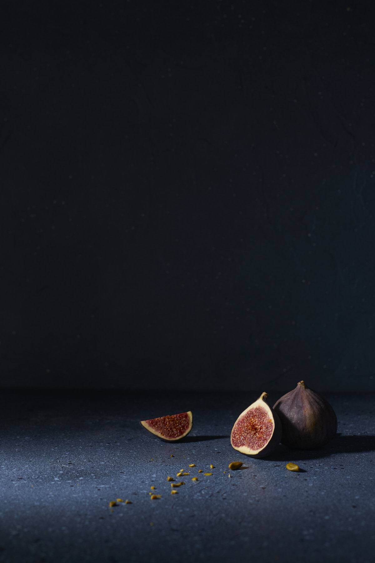 Figues sur fond bleu sombre avec grand espace négatif en photographie culinaire moody