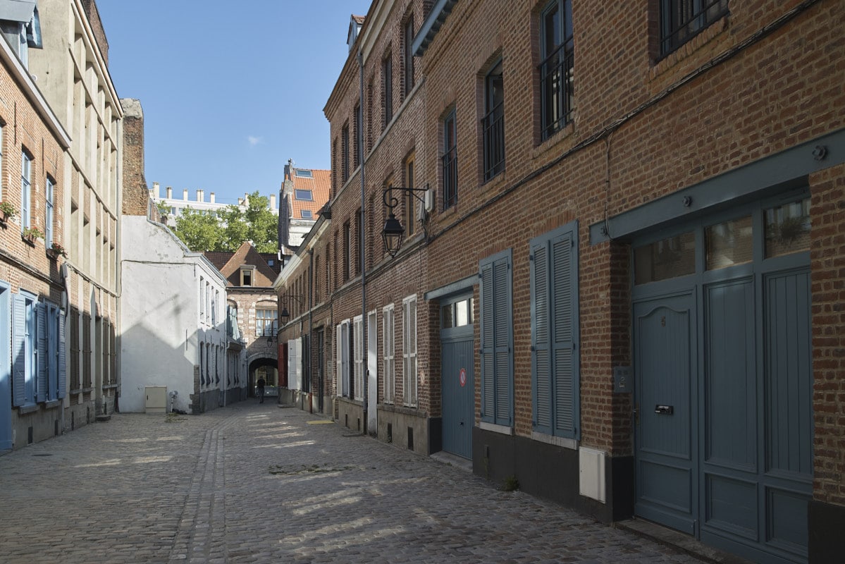 Une cour pavée, murs étroits et volets colorés