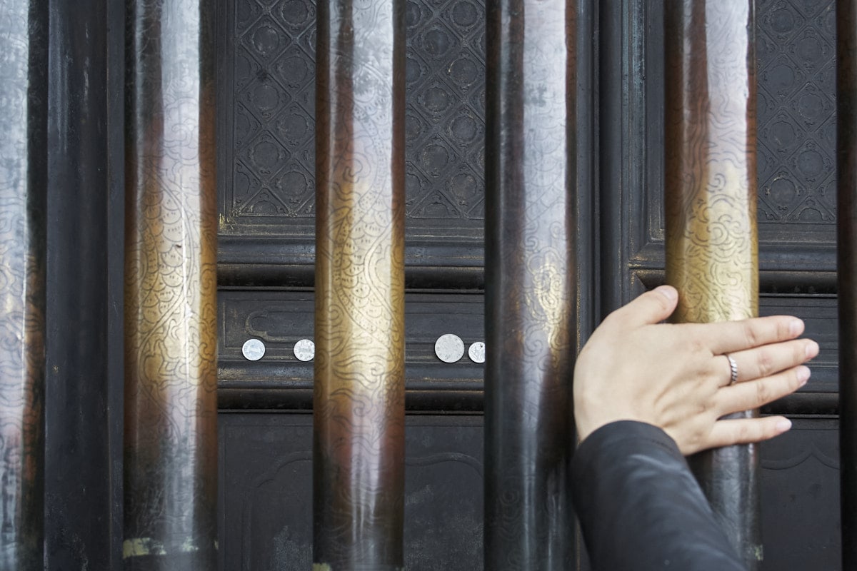 Les gens touchent les barres métalliques du sanctuaire.