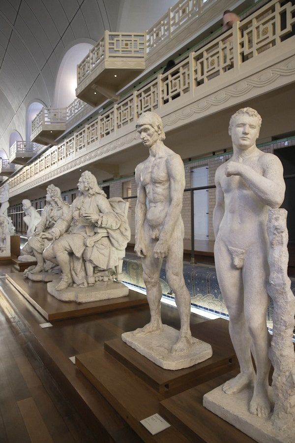 Des statues blanches d'hommes le long de la piscine