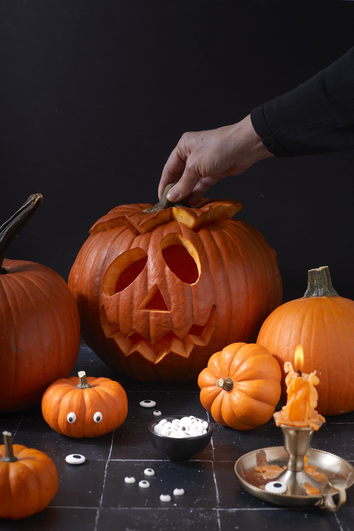 Lanterne d’Halloween entourée de courges, d’yeux en sucre et d’une bougie dans un bougeoir en laiton